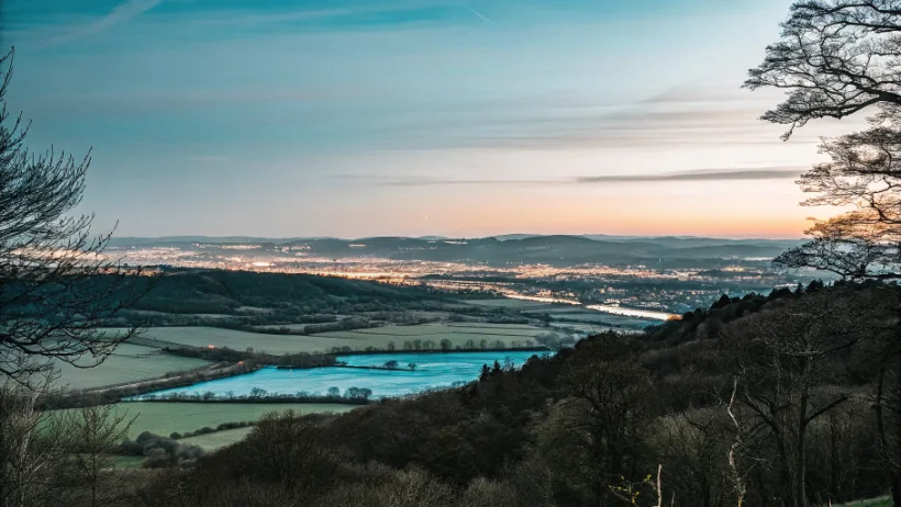 Cumbrian valley at dusk with distant town lights visible